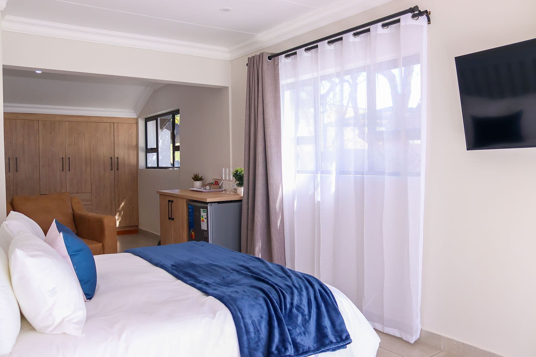 Navy Room: room with sheer curtains and wall-mounted TV